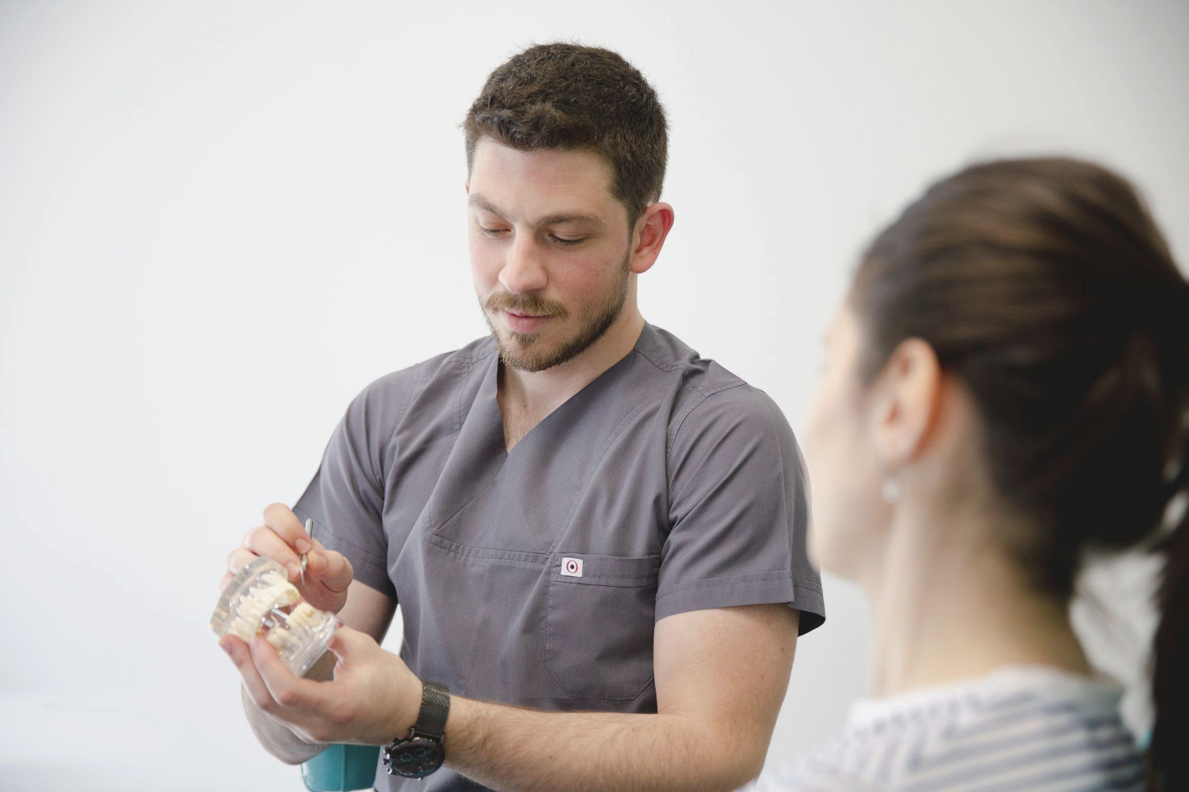 Zahnarzt erklärt einer Patientin ein Kiefermodell