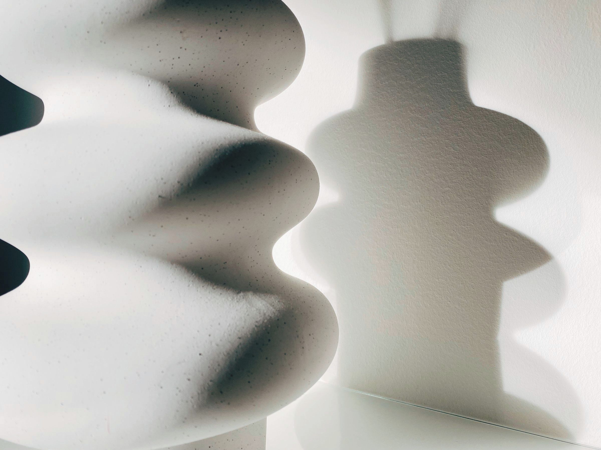 Schatten einer Keramikvase auf einer hellen Wand