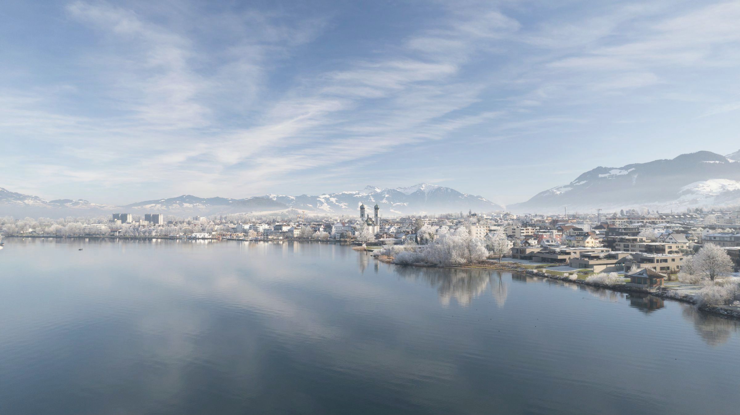 Ruhiger See mit Spiegelung der Berge im Morgenlicht